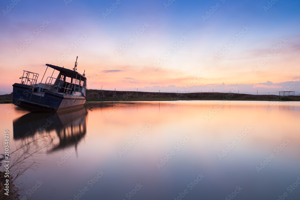 Reflection of boat on water at sunset time