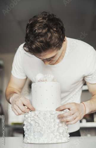 Young attractive man decorating cake