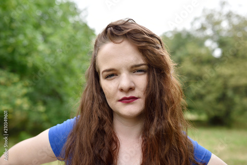 Portrait of confident redhead girl looking at camera with contempt