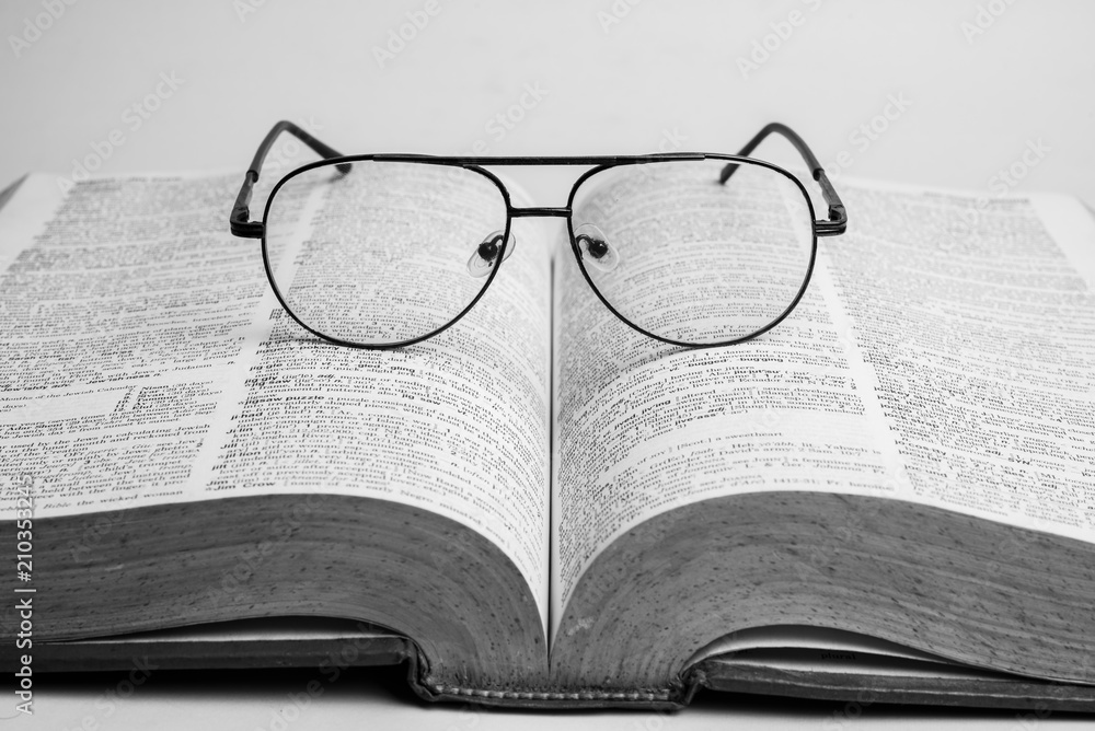 Glasses on open book with black and white style Glasses on open book with black and white style