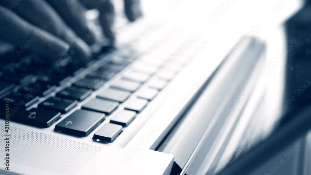 Fingers typing on a laptop, blue tone Fingers typing on a laptop, blue tone
