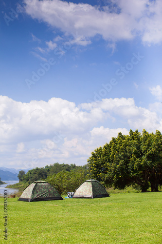 Camping tent on green grass field under clear sky 