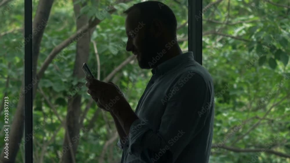 Silhouette of man using smartphone standing by window at home
Silhouette of man using smartphone standing by window at home