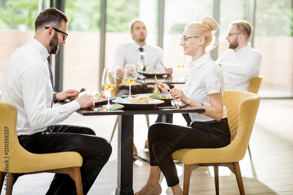 Business people having lunch with delicious meals sitting in pairs at the modern restaurant Business people having lunch with delicious meals sitting in pairs at the modern restaurant