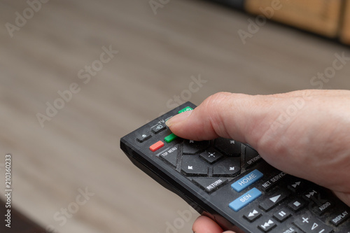 Woman using a black remote for zapping in tv