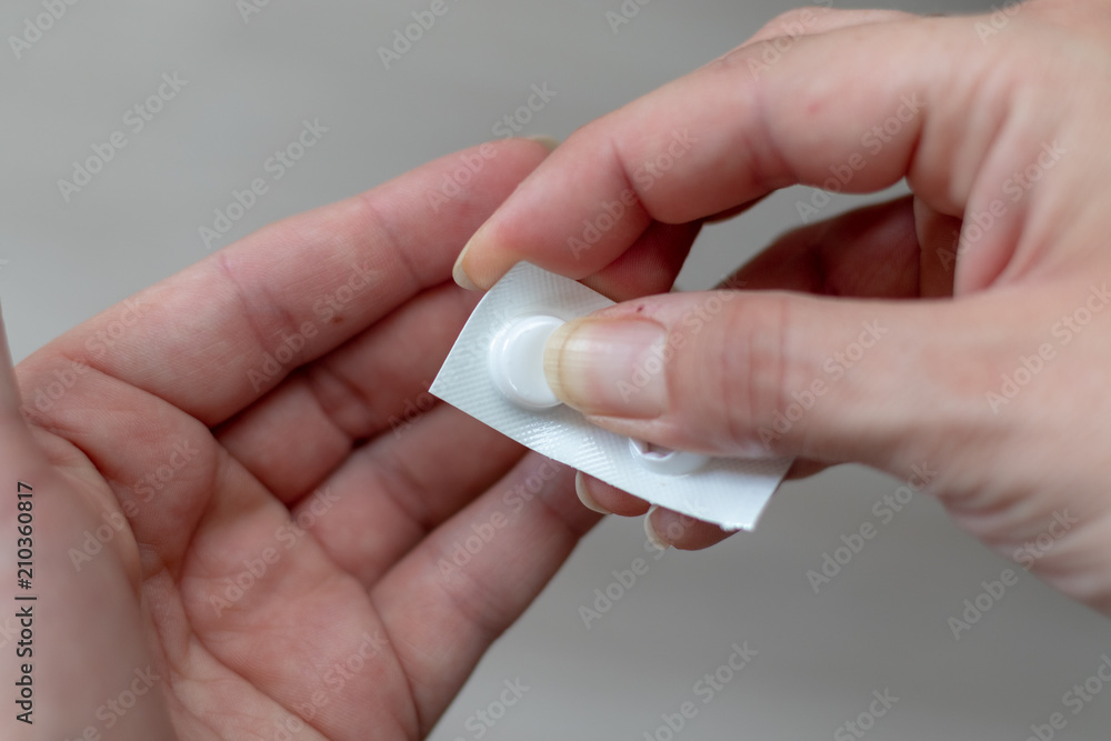 Small white package with tablets in the hands of a woman Small white package with tablets in the hands of a woman