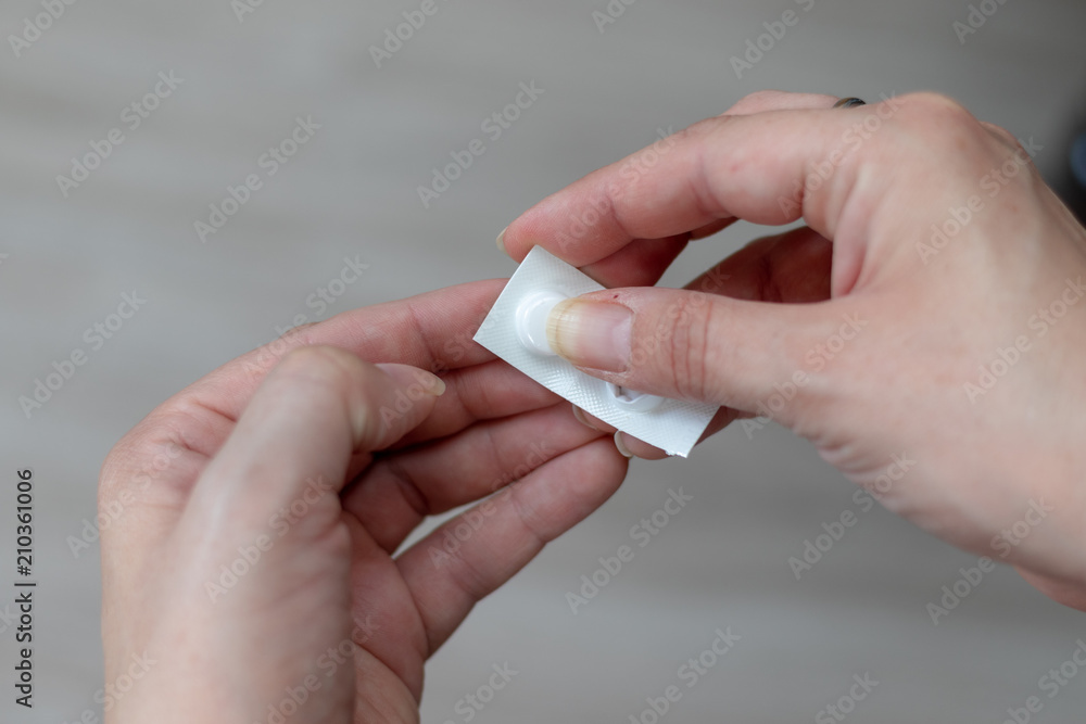 Small white package with tablets in the hands of a woman Small white package with tablets in the hands of a woman