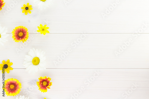 White daisies and garden flowers on a white wooden table. The flowers are arranged side, empty space left on the other side. © liptakrobi