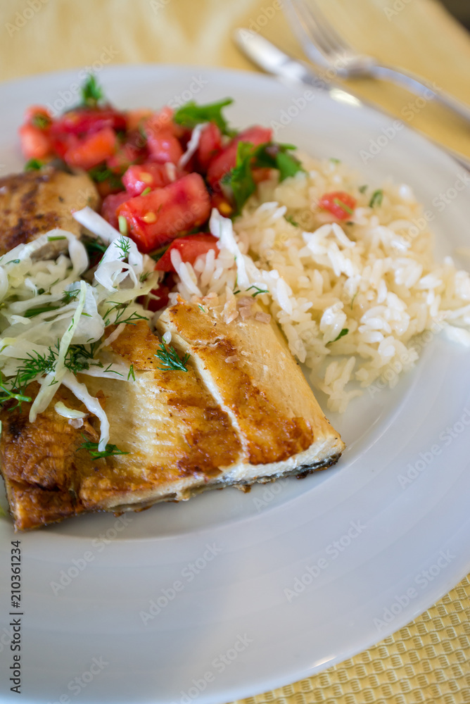 fried fish with rice cabbage and tomatoes on plate