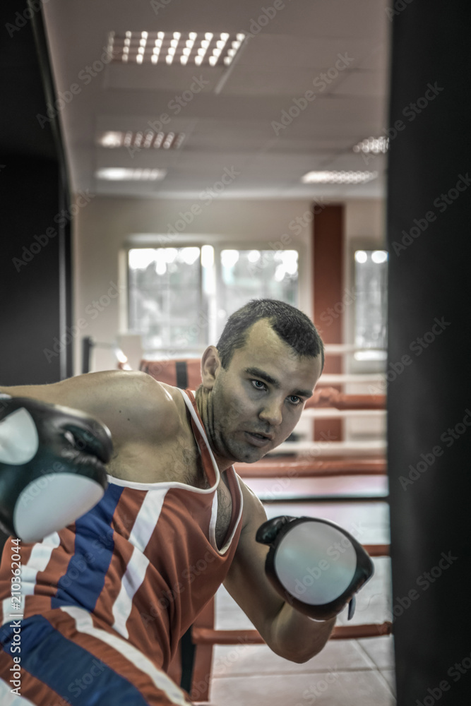 young boxer sportsman performs sports exercises with a boxing pear in the gym. young boxer sportsman performs sports exercises with a boxing pear in the gym.