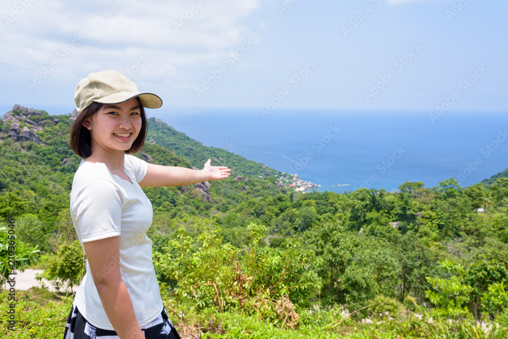 Women tourists raise hand and pointing the finger at the sea on high viewpoint to see the beautiful nature landscape of Koh Tao island is a famous attractions in Surat Thani, Thailand