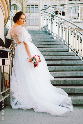 Adorable caucasian bride in white flowing wedding dress