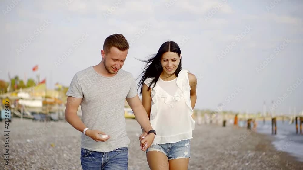 husband and wife stroll along the beach to hold hands, they chat with each other husband and wife stroll along the beach to hold hands, they chat with each other
