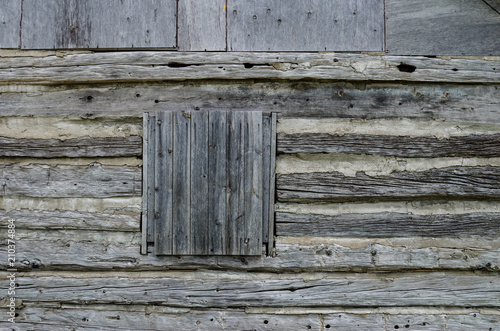 Close-up of a boarded up window on a log cabin