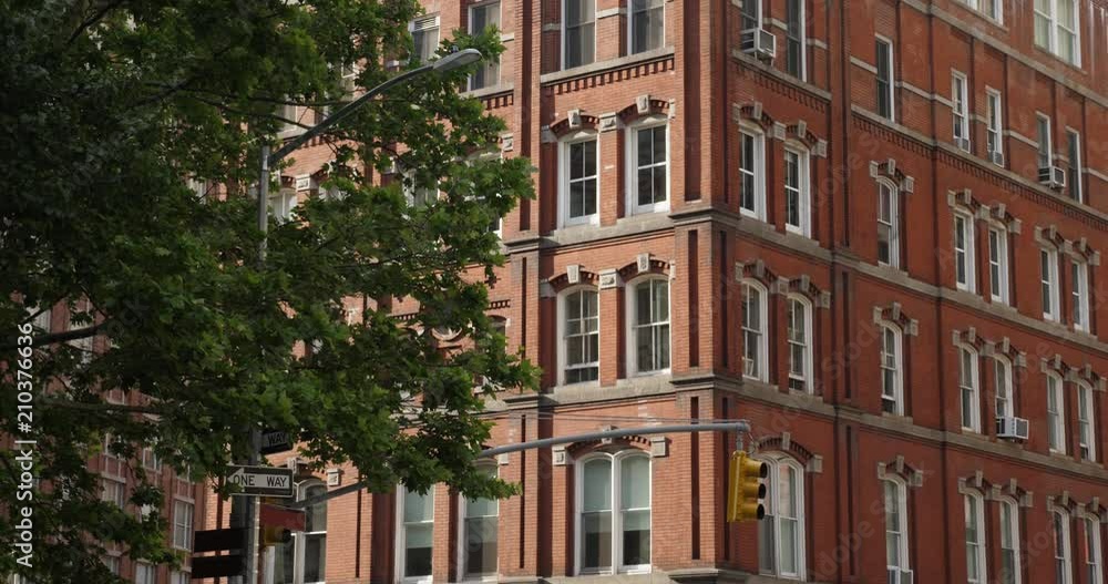 A daytime exterior establishing shot of a typical red brick apartment building on a sunny summer day. A daytime exterior establishing shot of a typical red brick apartment building on a sunny summer day.