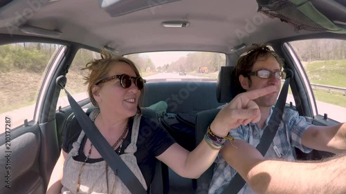 Happy woman pointing and man driving in a car on a highway photo