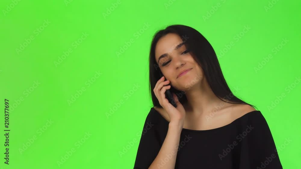 Young beautiful happy dark haired woman wearing elegant black dress using her smart phone on chromakey background. Cheerful attractive woman smiling, while talking on the phone. Young beautiful happy dark haired woman wearing elegant black dress using her smart phone on chromakey background. Cheerful attractive woman smiling, while talking on the phone.