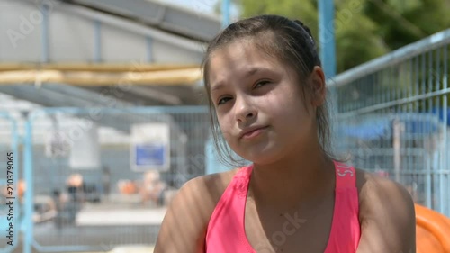 Adorable little girl pours a drink near water pool. portrait cute girl in pink swimsuit near pool, eating chips