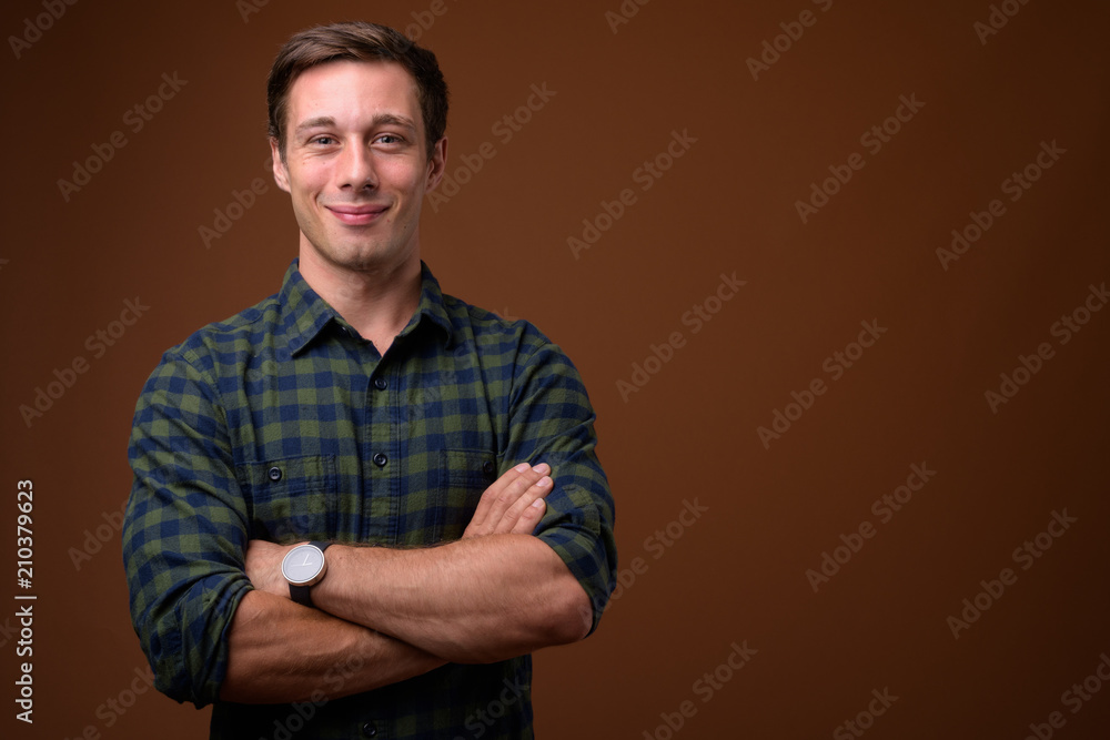 Obraz premium Young handsome man against brown background