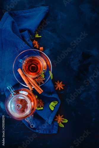 Tea cup and a tiny teapot with lemon slices and mint leaves on a dark background. Vibrant colors hot drink still life with copy space. Tea time flat lay