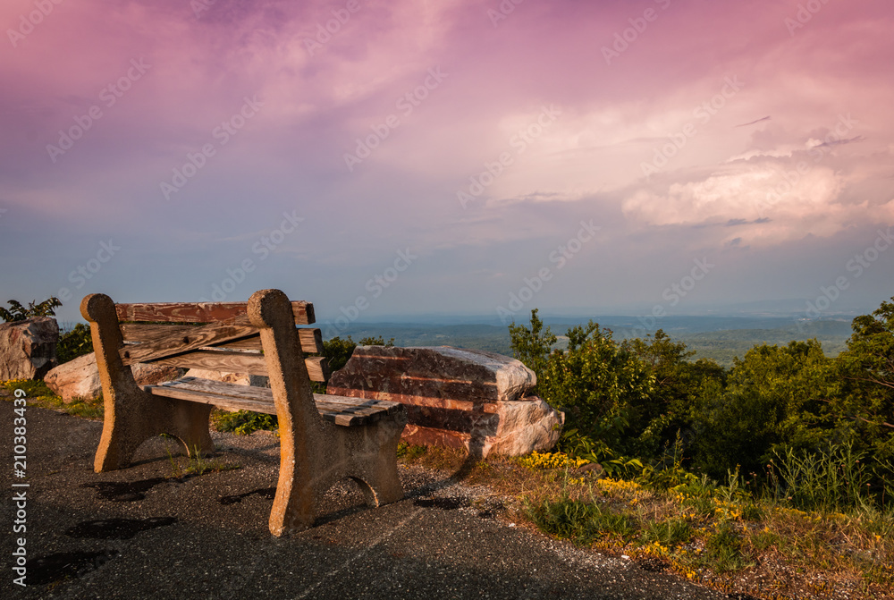 A lone bench faces the mountains under a stormy sunset at High Point State Park, the top of NJ, in late spring