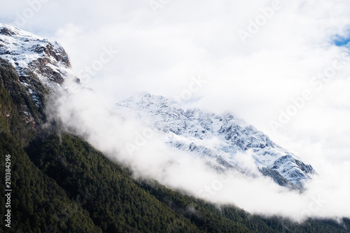 The stunning scene of a foggy and rocky mountain covered with snow at Eglinton Valley on the road to Milford Sound photo