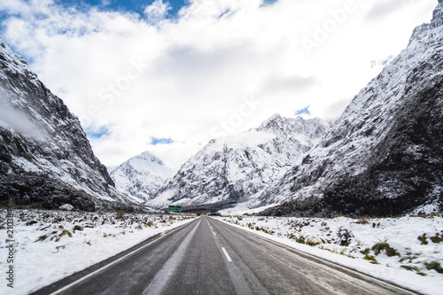 The stunning scenery of a rocky mountain and trees covered with a white snow. A road to Milford Sound. A filmed while driving.