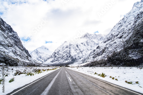 The stunning scenery of a rocky mountain and trees covered with a white snow. A road to Milford Sound. A filmed while driving.
