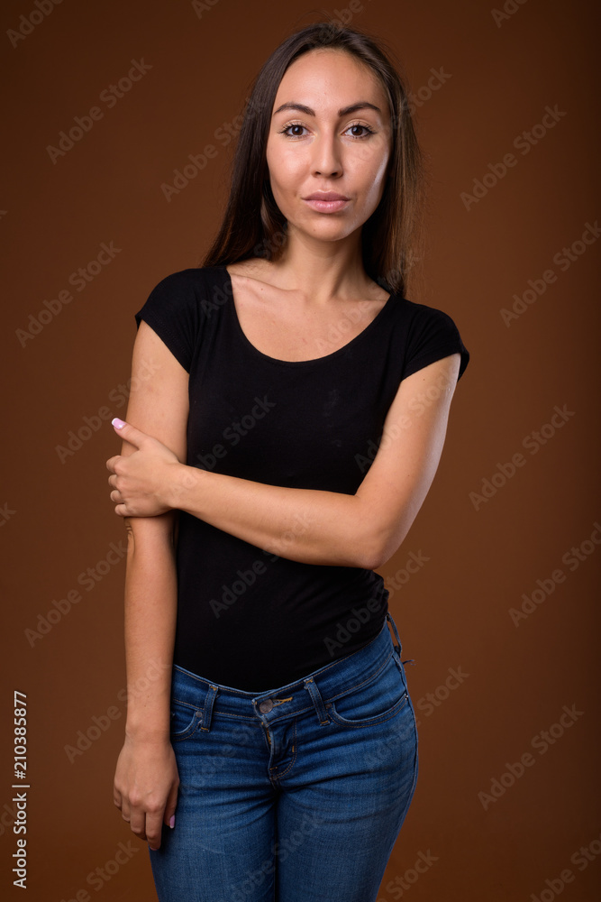 Studio shot of young beautiful woman against brown background Studio shot of young beautiful woman against brown background