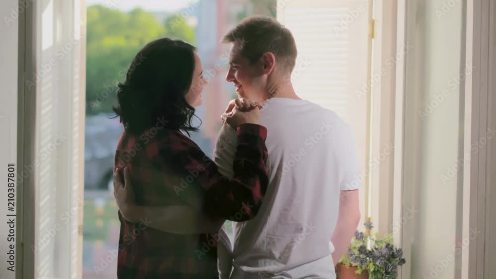 Happy young parents standing near open window Happy young parents standing near open window