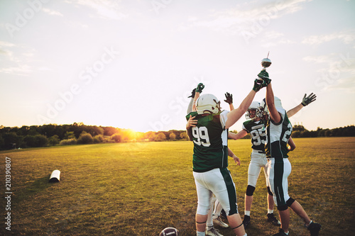 Fototapeta Naklejka Na Ścianę i Meble -  Excited football players standing outside celebrating with a cha