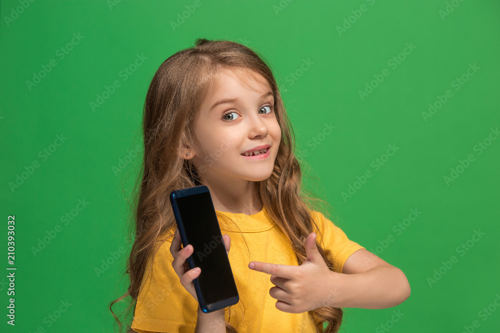 The happy teen girl standing and smiling against green background. The happy teen girl standing and smiling against green background.
