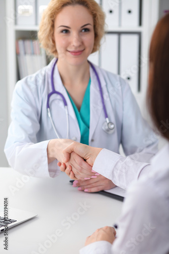 Doctor and patient shaking hands, close-up. Medicine, healthcare and trust concept