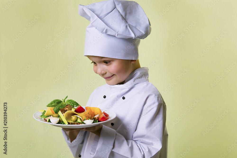 funny boy chef cooked salad with vegetables, cheese and ham on a plate funny boy chef cooked salad with vegetables, cheese and ham on a plate