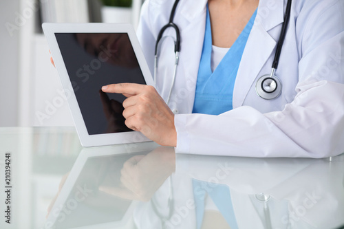 Wallpaper Mural Female doctor using tablet computer while sitting at the workplace, close-up of hands. Medicine, healthcare and help concept Torontodigital.ca