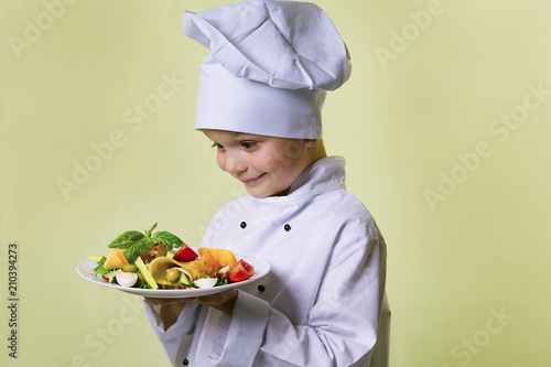 funny boy chef cooked salad with vegetables, cheese and ham on a plate