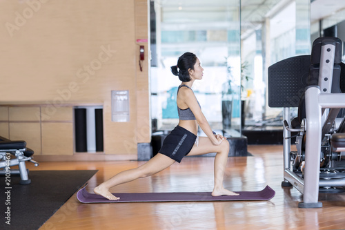 Female athlete doing a stretch on fitness center
