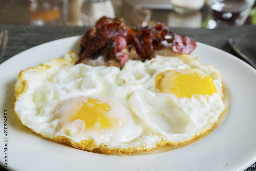 Fried egg and bacon slices on the plate Fried egg and bacon slices on the plate
