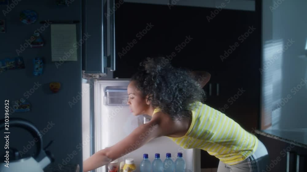 Black Woman Looking into Fridge For Midnight Snack Black Woman Looking into Fridge For Midnight Snack