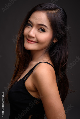 Young beautiful Asian woman against gray background
