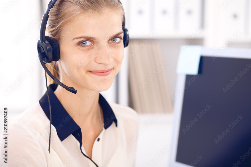 Call center operator. Blonde business woman in a headset in white office with pc computer Call center operator. Blonde business woman in a headset in white office with pc computer