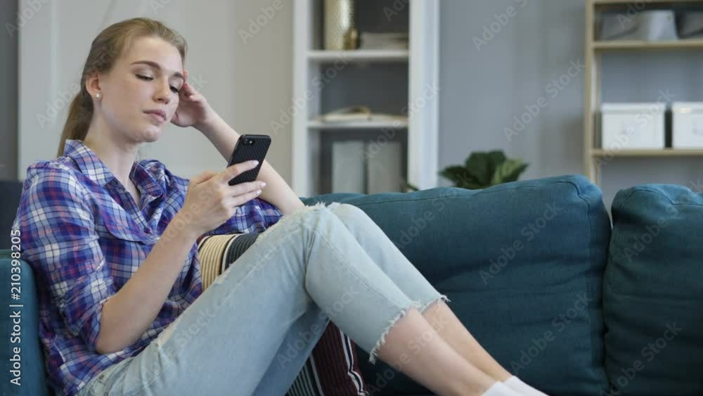 Young Woman Using Smart Phone while Relaxing on Couch Young Woman Using Smart Phone while Relaxing on Couch