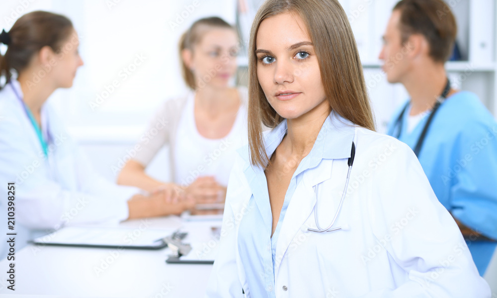 Happy doctor woman with medical staff at the background in hospital office Happy doctor woman with medical staff at the background in hospital office