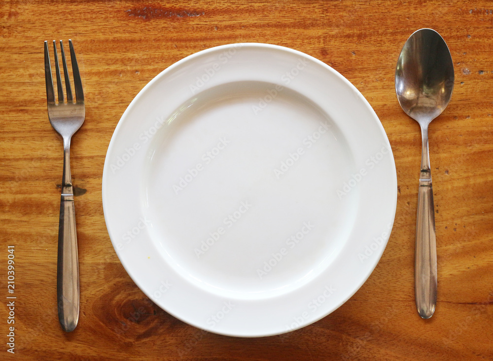 Empty plate on wooden table with fork and spoon Empty plate on wooden table with fork and spoon