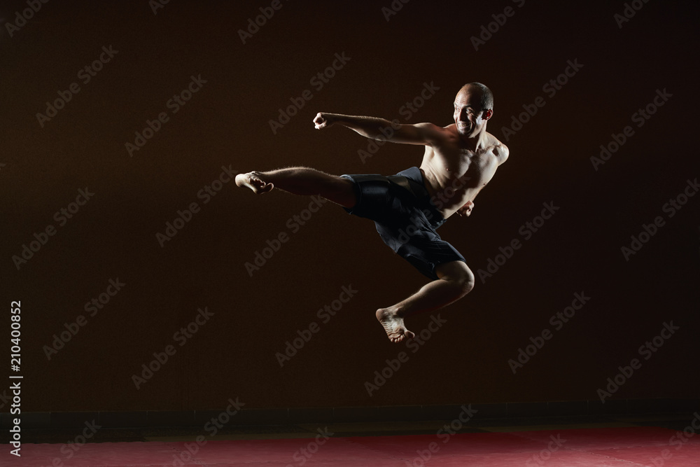 Adult athlete trains a kick in the jump to the side