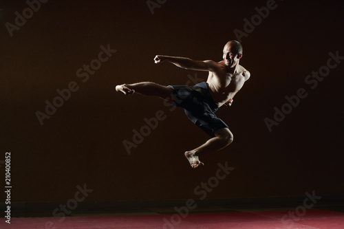 Adult athlete trains a kick in the jump to the side © andreyfire