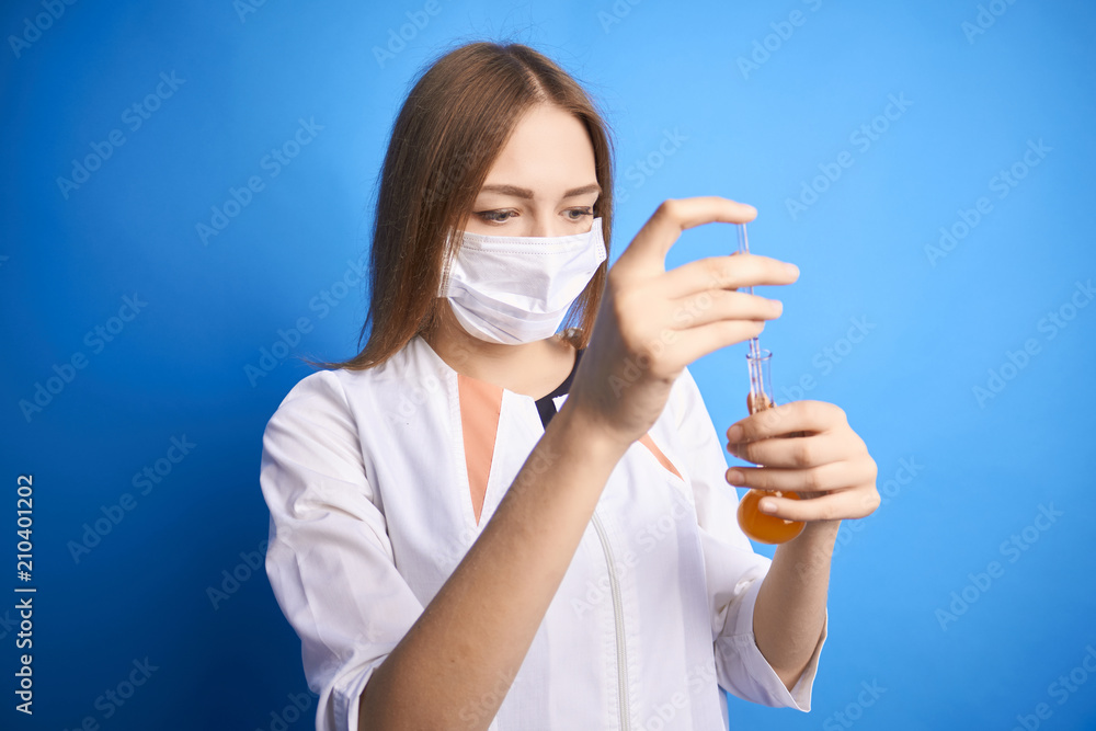 .girl in a medical suit holds a bottle in her hands