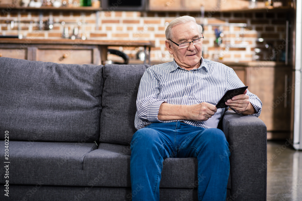 Positive elderly man reading an e book