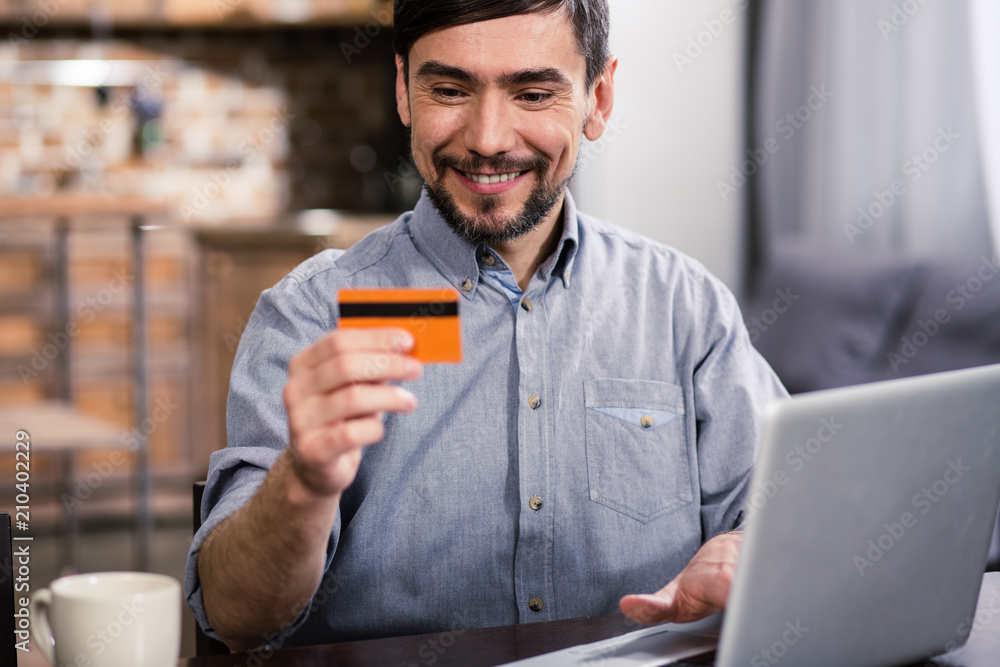 Waist up of cheerful man holding his credit card Waist up of cheerful man holding his credit card