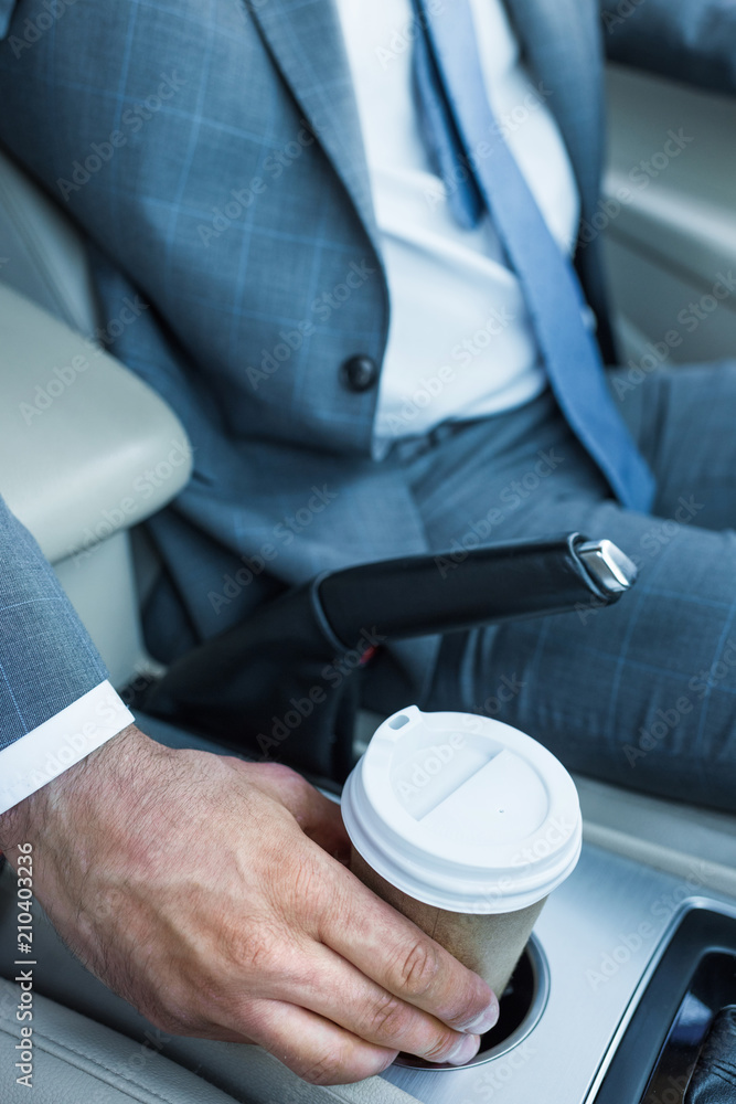 cropped shot of businessman taking coffee to go in car